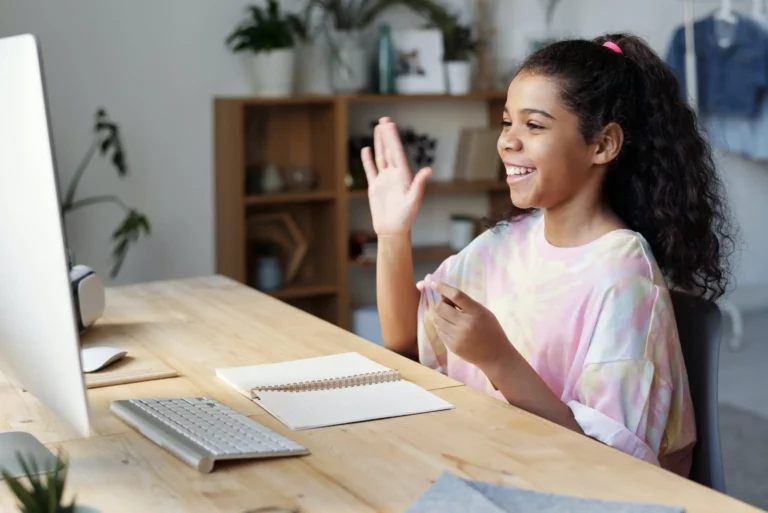 student waving at computer screen